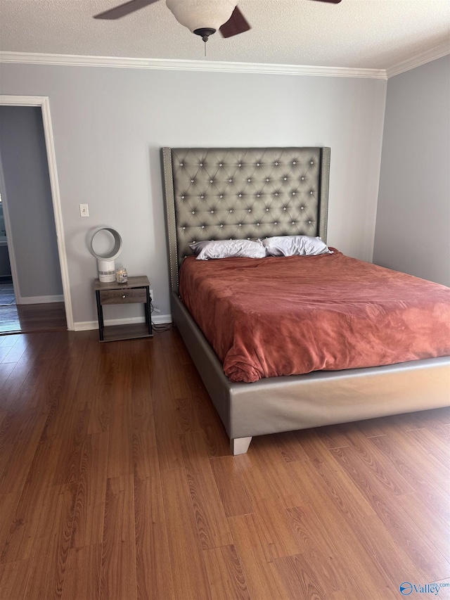 bedroom featuring baseboards, a textured ceiling, wood finished floors, and ornamental molding