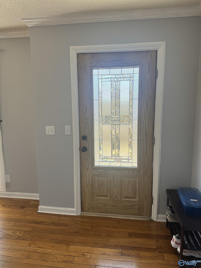 entrance foyer with baseboards, a textured ceiling, crown molding, and hardwood / wood-style flooring