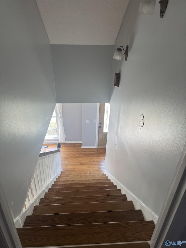 staircase with a wealth of natural light, baseboards, and wood finished floors