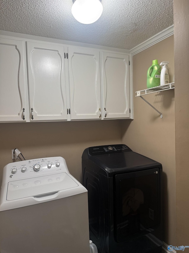 clothes washing area featuring cabinet space, washing machine and dryer, and a textured ceiling