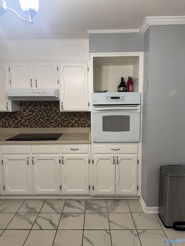 kitchen featuring black electric stovetop, marble finish floor, under cabinet range hood, and oven