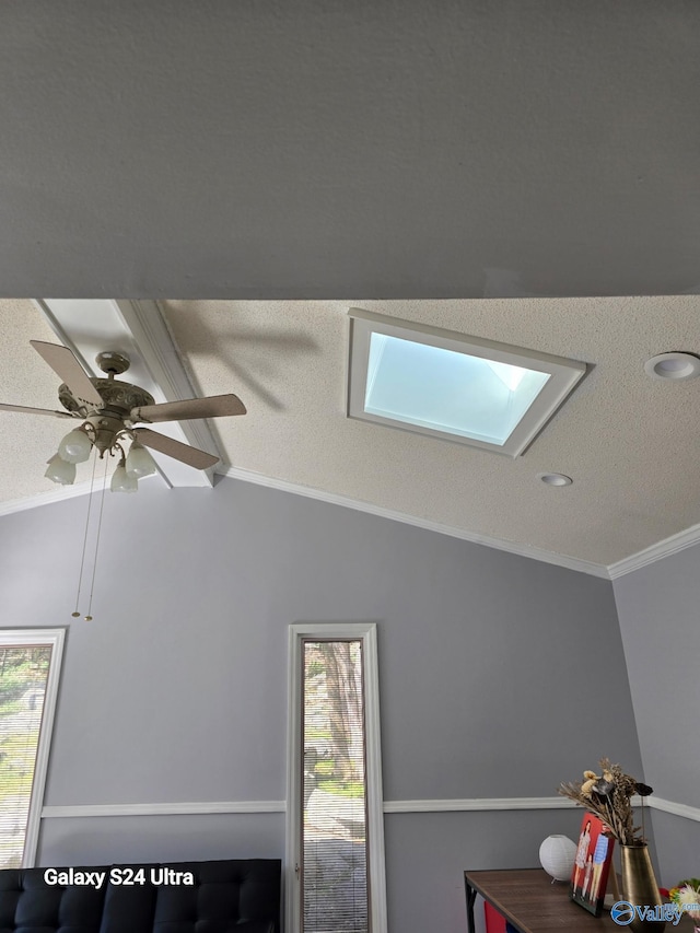 interior details featuring ceiling fan, a textured ceiling, a skylight, and crown molding