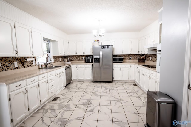 kitchen with a sink, marble finish floor, appliances with stainless steel finishes, and under cabinet range hood