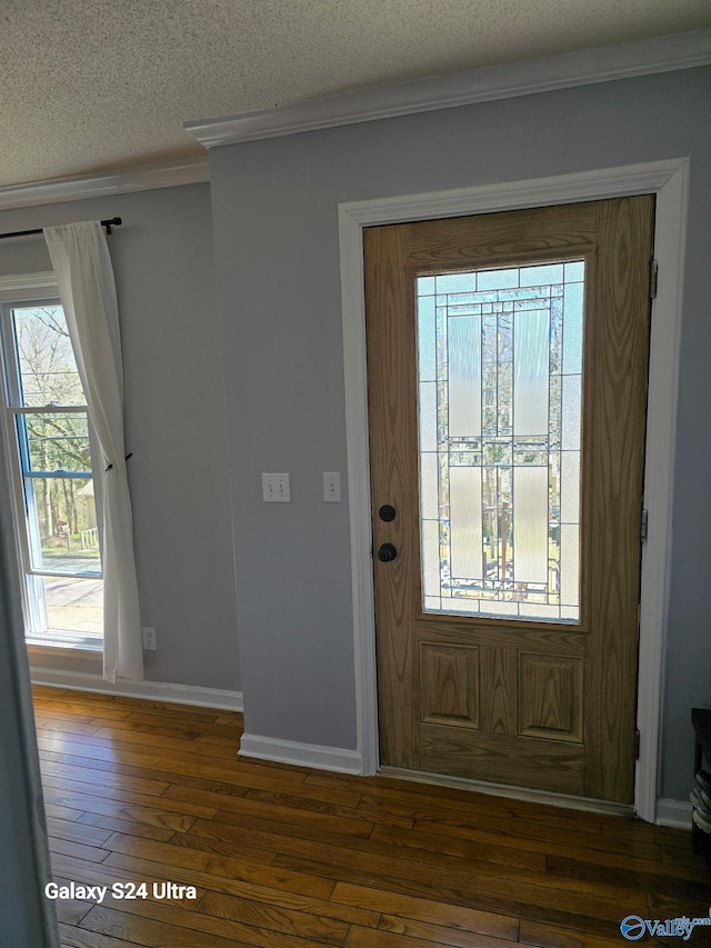 entrance foyer with hardwood / wood-style flooring, crown molding, baseboards, and a textured ceiling