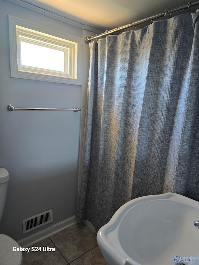 full bathroom featuring a shower with curtain, visible vents, a sink, tile patterned floors, and toilet