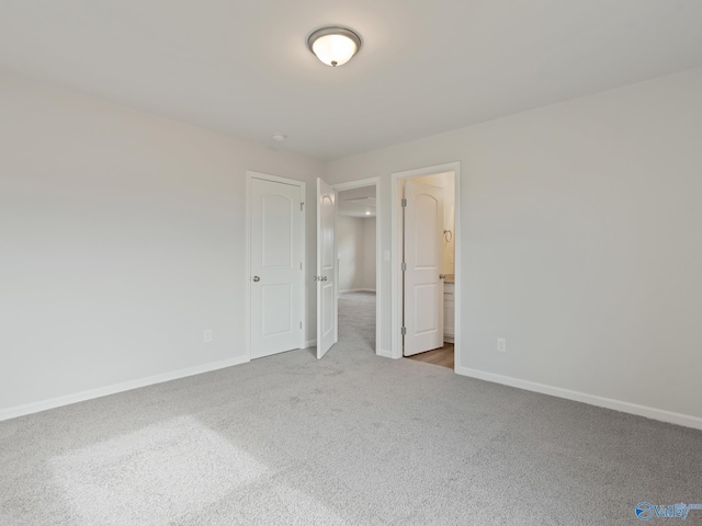 unfurnished bedroom featuring ensuite bath and light colored carpet