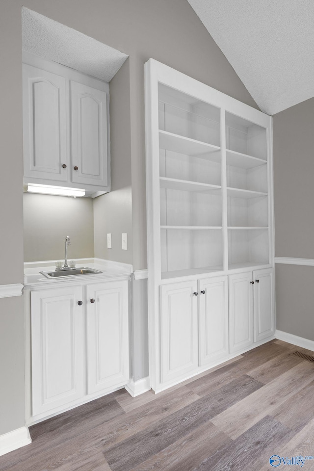 127 Patdean Dr, Huntsville, AL 35811 - indoor wet bar featuring light wood-style flooring, lofted ceiling, and a textured ceiling