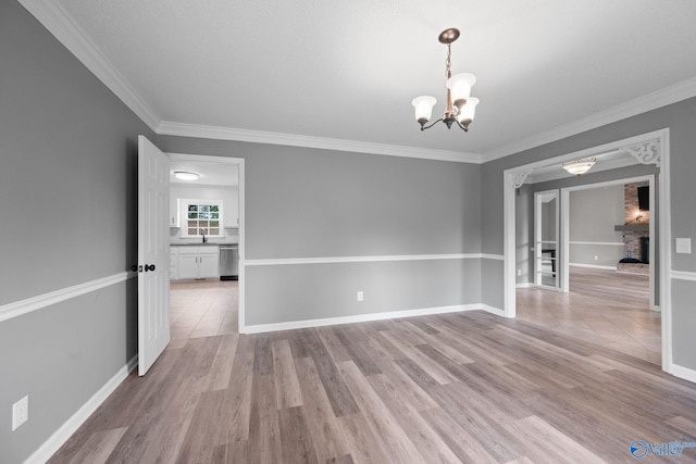 127 Patdean Dr, Huntsville, AL 35811 - empty room with a chandelier, ornamental molding, light wood-style flooring, and a large fireplace