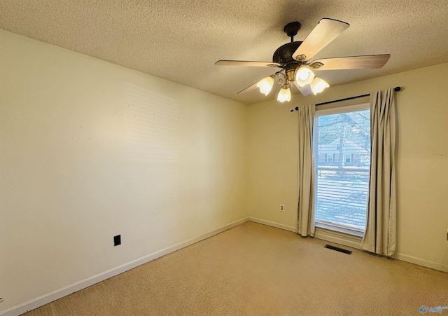 empty room with light carpet, baseboards, visible vents, a ceiling fan, and a textured ceiling