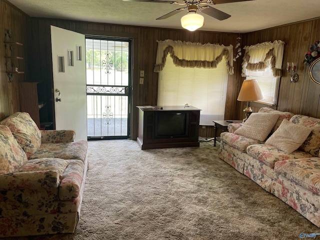 carpeted living room with wooden walls and ceiling fan