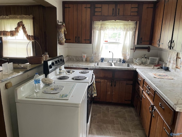 kitchen featuring a wealth of natural light, white electric stove, light countertops, and a sink