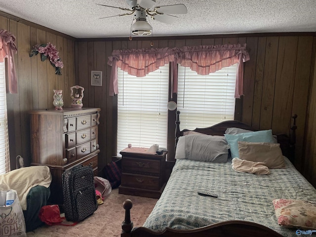 carpeted bedroom featuring wooden walls, a textured ceiling, and a ceiling fan