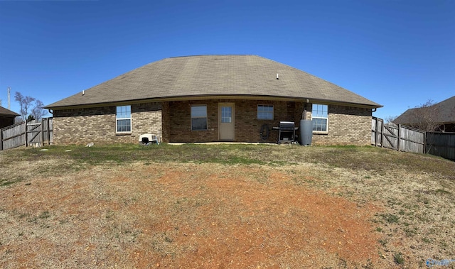 back of property with brick siding and a fenced backyard