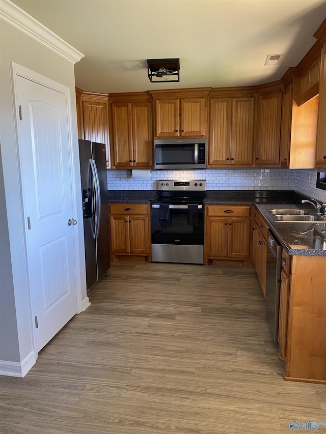 kitchen featuring a sink, decorative backsplash, appliances with stainless steel finishes, and brown cabinets