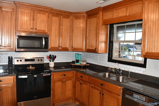 kitchen with decorative backsplash, brown cabinets, a sink, and appliances with stainless steel finishes