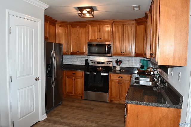 kitchen featuring tasteful backsplash, brown cabinets, a sink, and appliances with stainless steel finishes