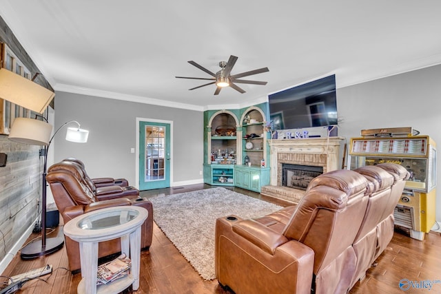 living room with crown molding, ceiling fan, wood-type flooring, and a fireplace