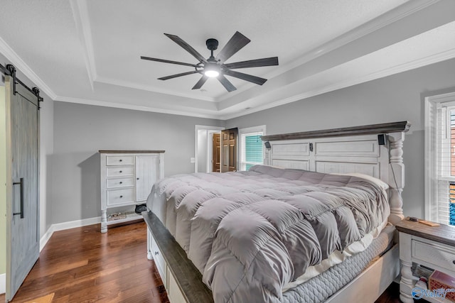 bedroom featuring dark hardwood / wood-style floors, multiple windows, ornamental molding, a tray ceiling, and a barn door