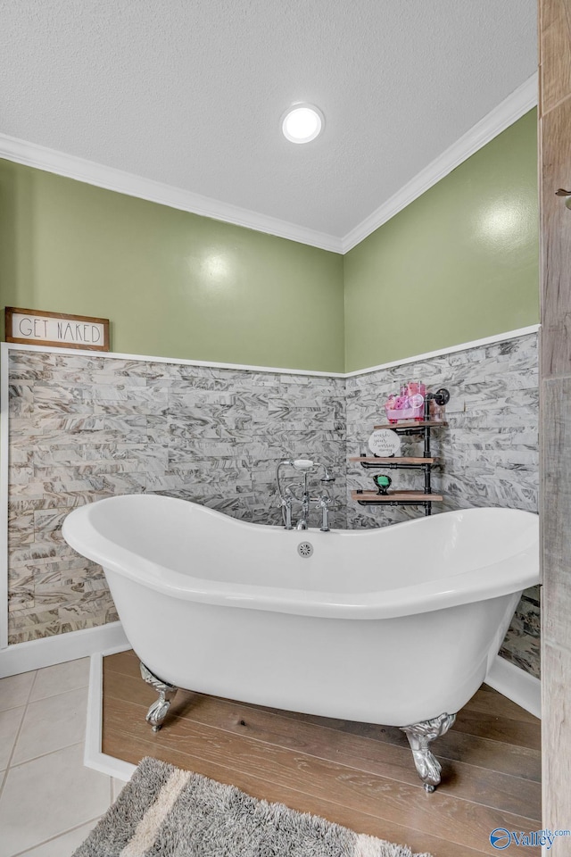 bathroom featuring crown molding, tile patterned floors, a tub, and a textured ceiling