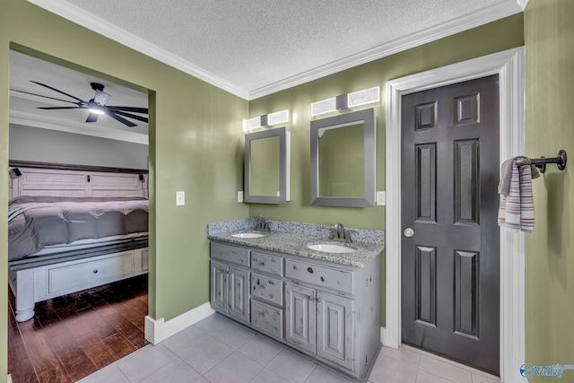 bathroom with a textured ceiling, ornamental molding, vanity, ceiling fan, and tile patterned flooring