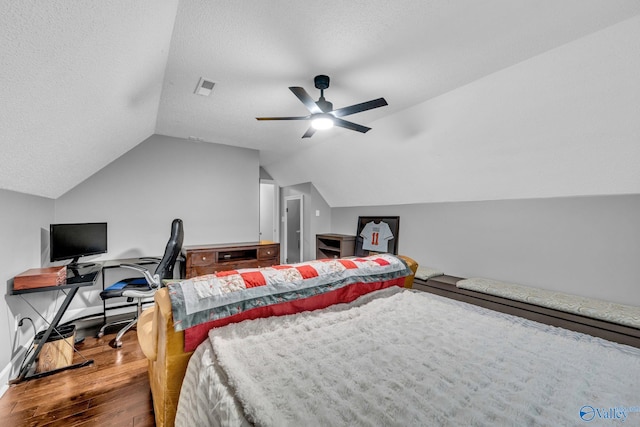 bedroom with ceiling fan, hardwood / wood-style flooring, vaulted ceiling, and a textured ceiling