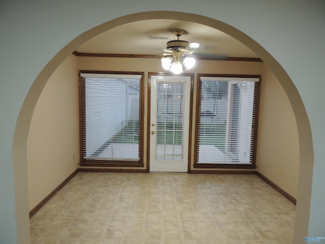 tiled empty room featuring ornamental molding and ceiling fan