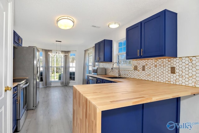 107 Harvest Glen Ln, Harvest, AL 35749 - kitchen featuring stainless steel appliances, butcher block counters, visible vents, decorative backsplash, and blue cabinetry