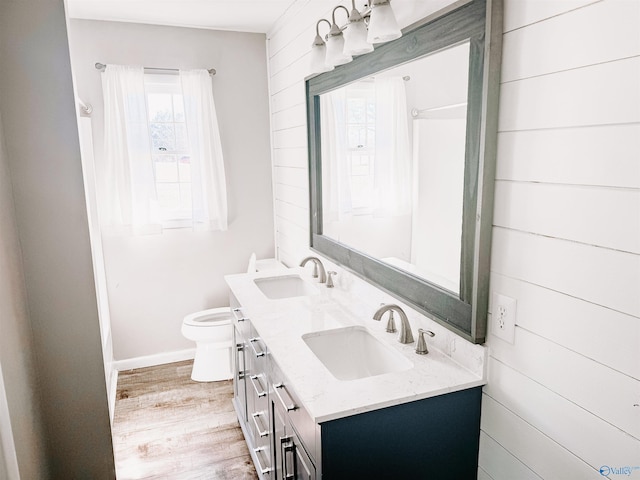 bathroom with double vanity, wood finished floors, a sink, and toilet