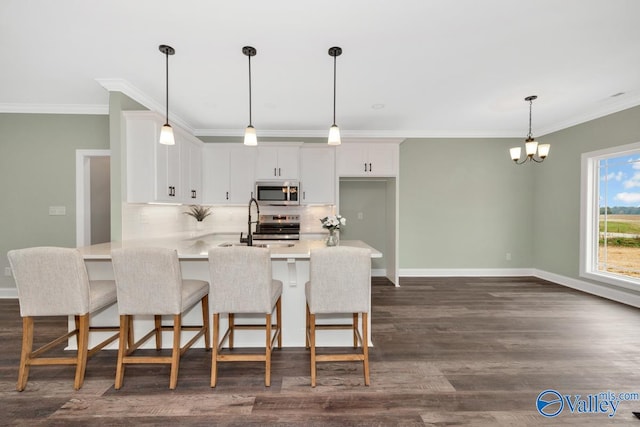 kitchen with stainless steel appliances, decorative light fixtures, white cabinets, dark wood-type flooring, and a breakfast bar area