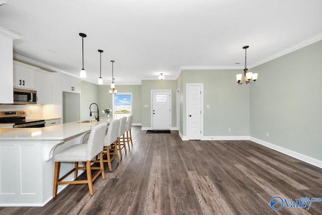 kitchen with appliances with stainless steel finishes, hanging light fixtures, dark hardwood / wood-style floors, and white cabinetry