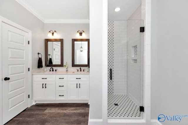 bathroom featuring vanity, wood-type flooring, ornamental molding, and a shower with door