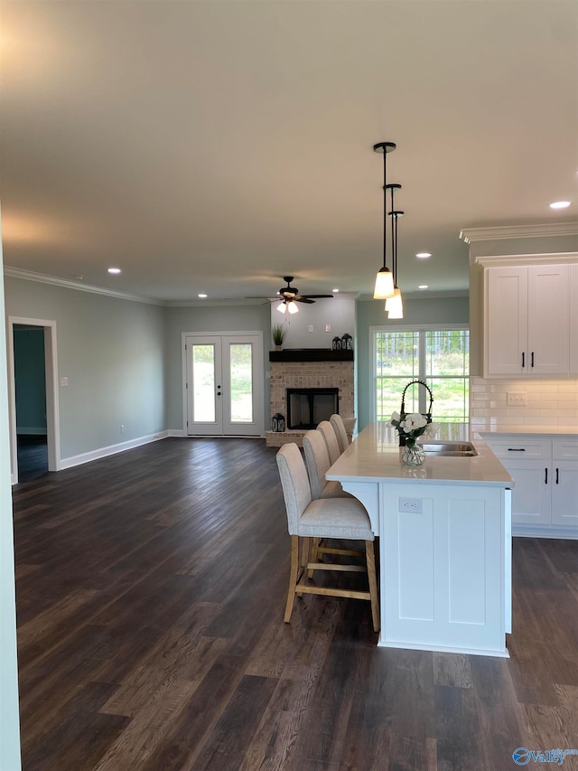 kitchen with sink, a fireplace, hanging light fixtures, white cabinetry, and dark hardwood / wood-style floors