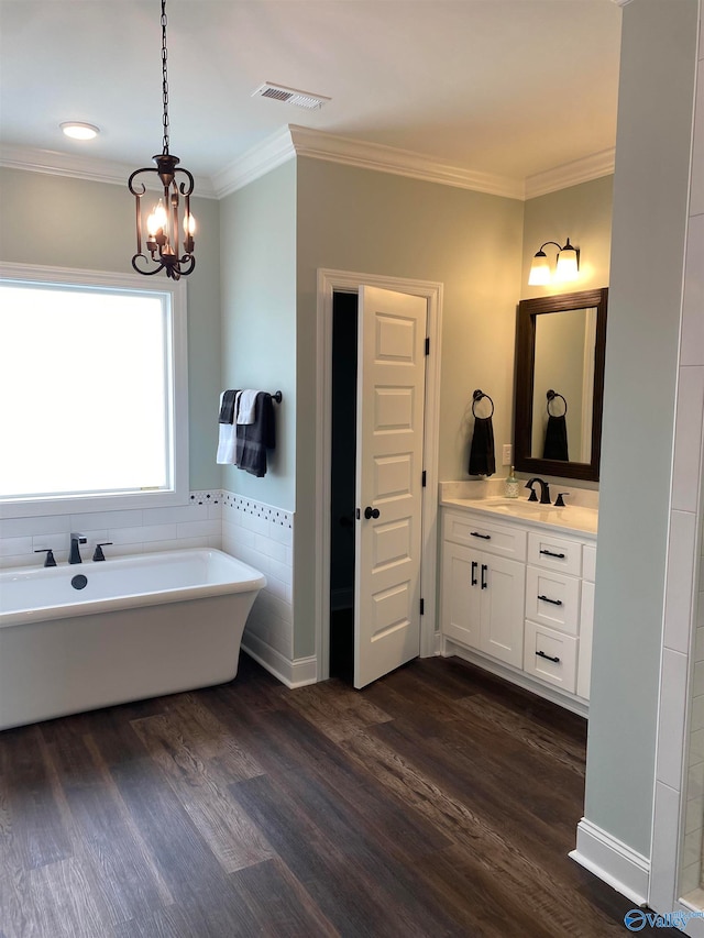 bathroom with hardwood / wood-style flooring, a chandelier, ornamental molding, vanity, and a tub to relax in