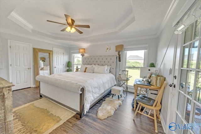 bedroom featuring ceiling fan, crown molding, a textured ceiling, a tray ceiling, and hardwood / wood-style flooring