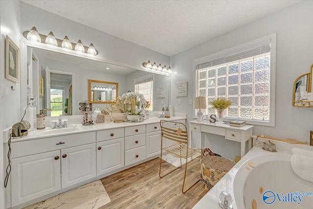 bathroom featuring a textured ceiling, hardwood / wood-style flooring, plenty of natural light, and a bathing tub