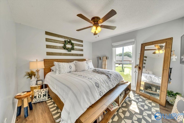 bedroom with ceiling fan, hardwood / wood-style floors, and a textured ceiling