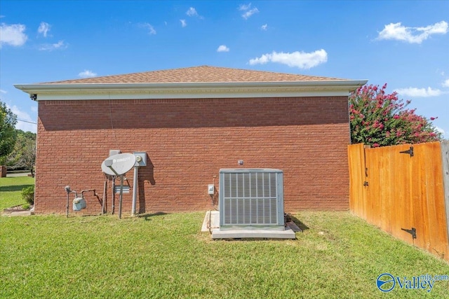 back of property featuring central air condition unit and a yard