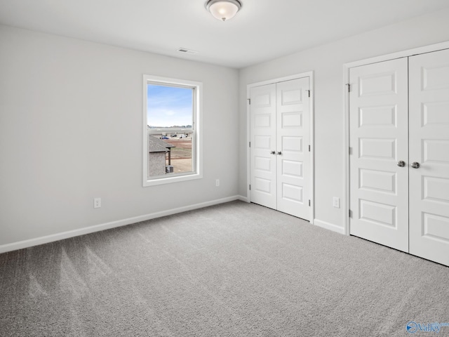 unfurnished bedroom with carpet floors and two closets