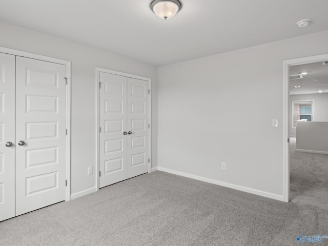 unfurnished bedroom featuring light colored carpet and two closets