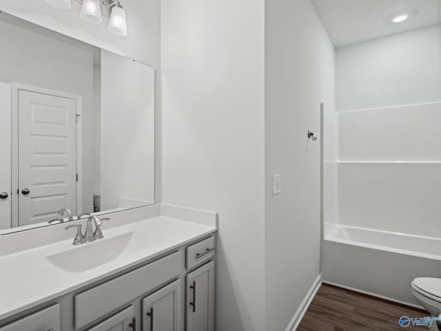 full bathroom featuring hardwood / wood-style flooring, vanity,  shower combination, and toilet