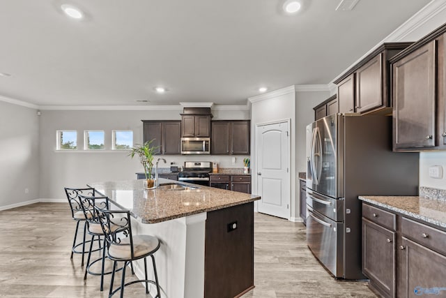 kitchen featuring light hardwood / wood-style flooring, sink, stainless steel appliances, and an island with sink