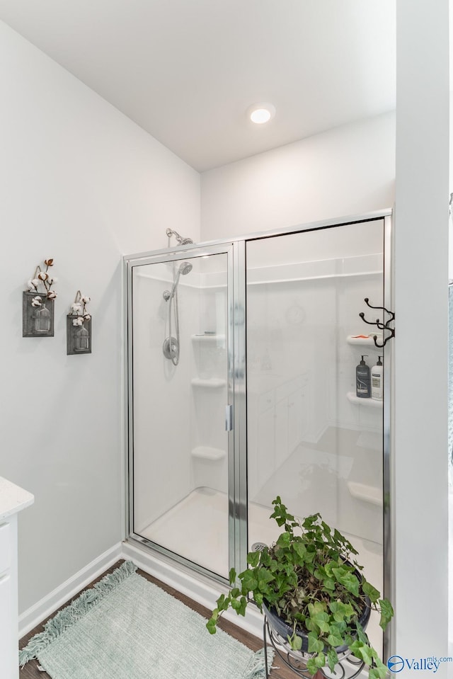 full bathroom with a shower stall and baseboards