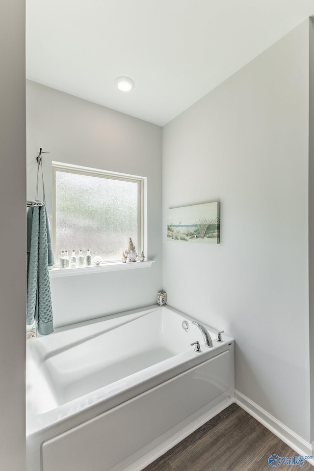 full bath featuring a bath, baseboards, and wood finished floors