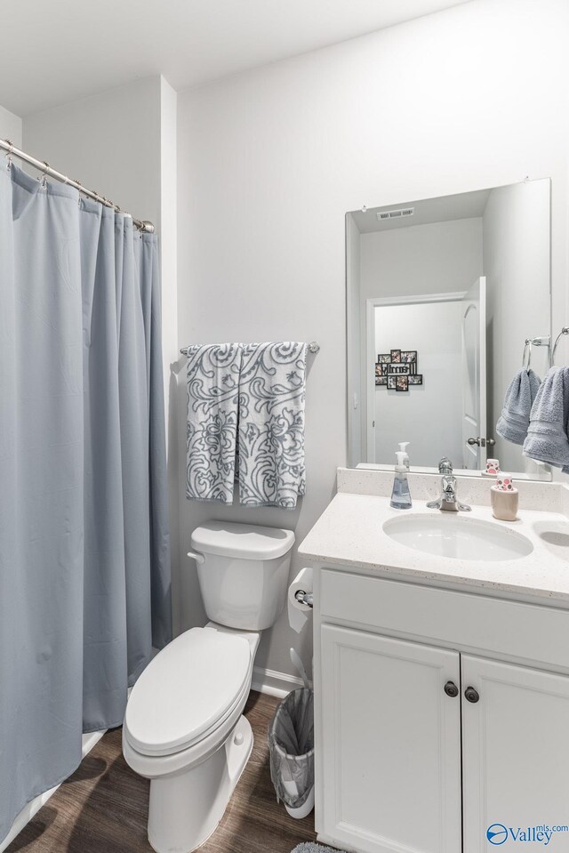 full bath with a shower with curtain, toilet, visible vents, wood finished floors, and vanity