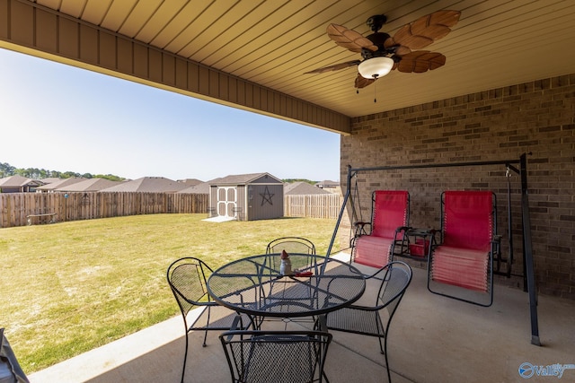 view of patio featuring outdoor dining area, ceiling fan, a shed, and a fenced backyard