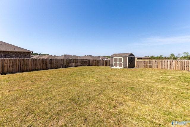 view of yard featuring a fenced backyard, a storage unit, and an outbuilding