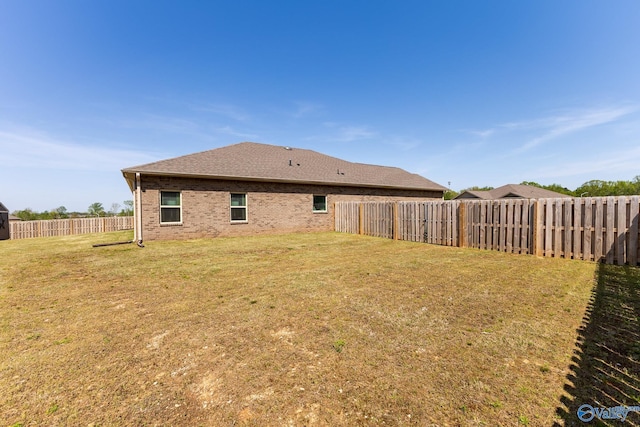 back of house featuring brick siding, a yard, a shingled roof, and a fenced backyard