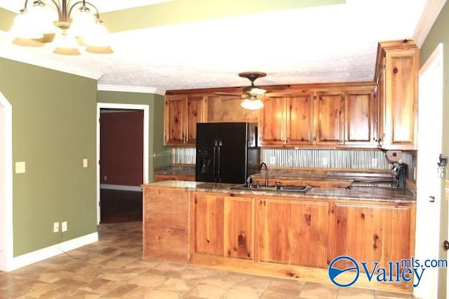 kitchen featuring pendant lighting, black fridge, sink, ceiling fan with notable chandelier, and crown molding