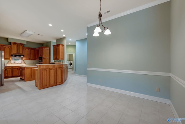 kitchen with baseboards, brown cabinets, decorative light fixtures, a center island, and light countertops