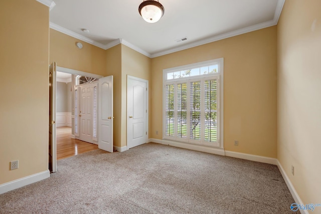 unfurnished bedroom with light colored carpet, crown molding, visible vents, and baseboards